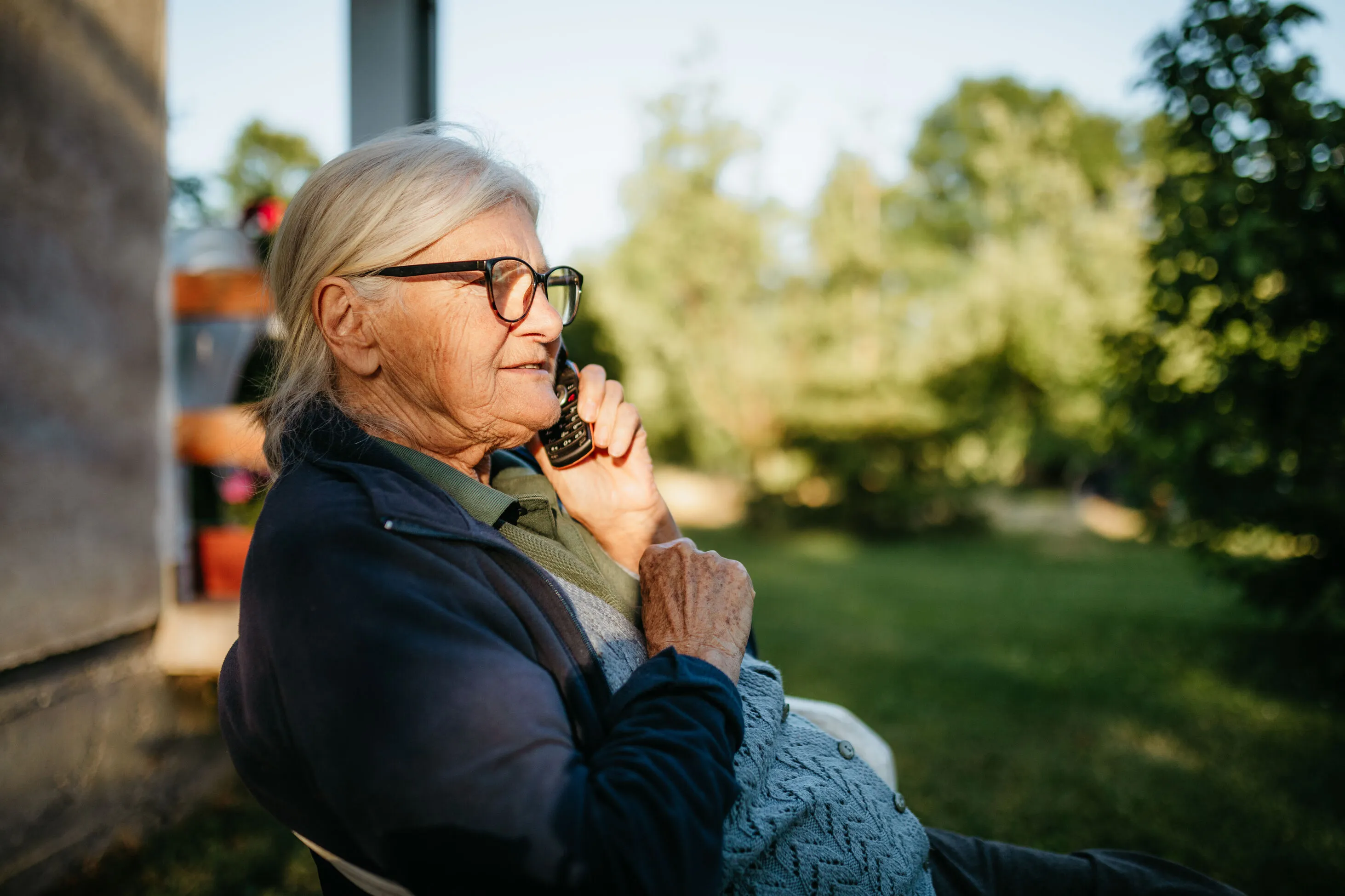 older woman on phone outside taking telehealth appointment