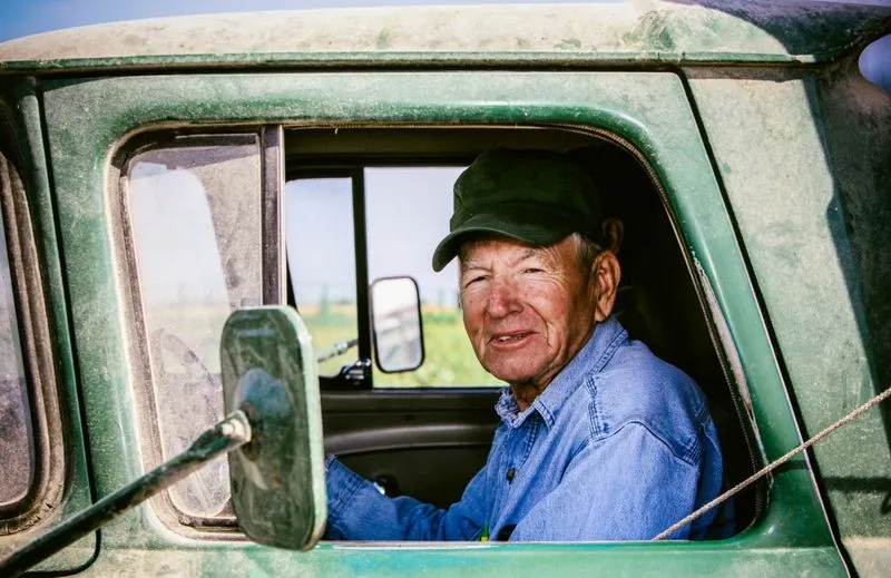 Elderly man in a dusty green pickup truck