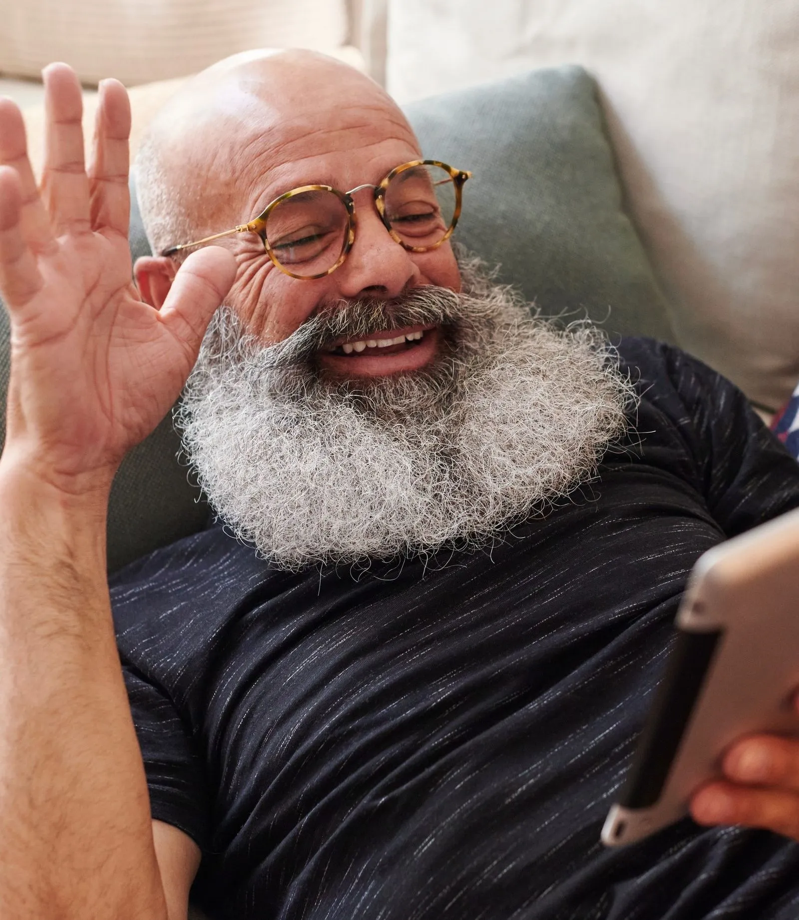 Man with silver beard smiles during a phone video call