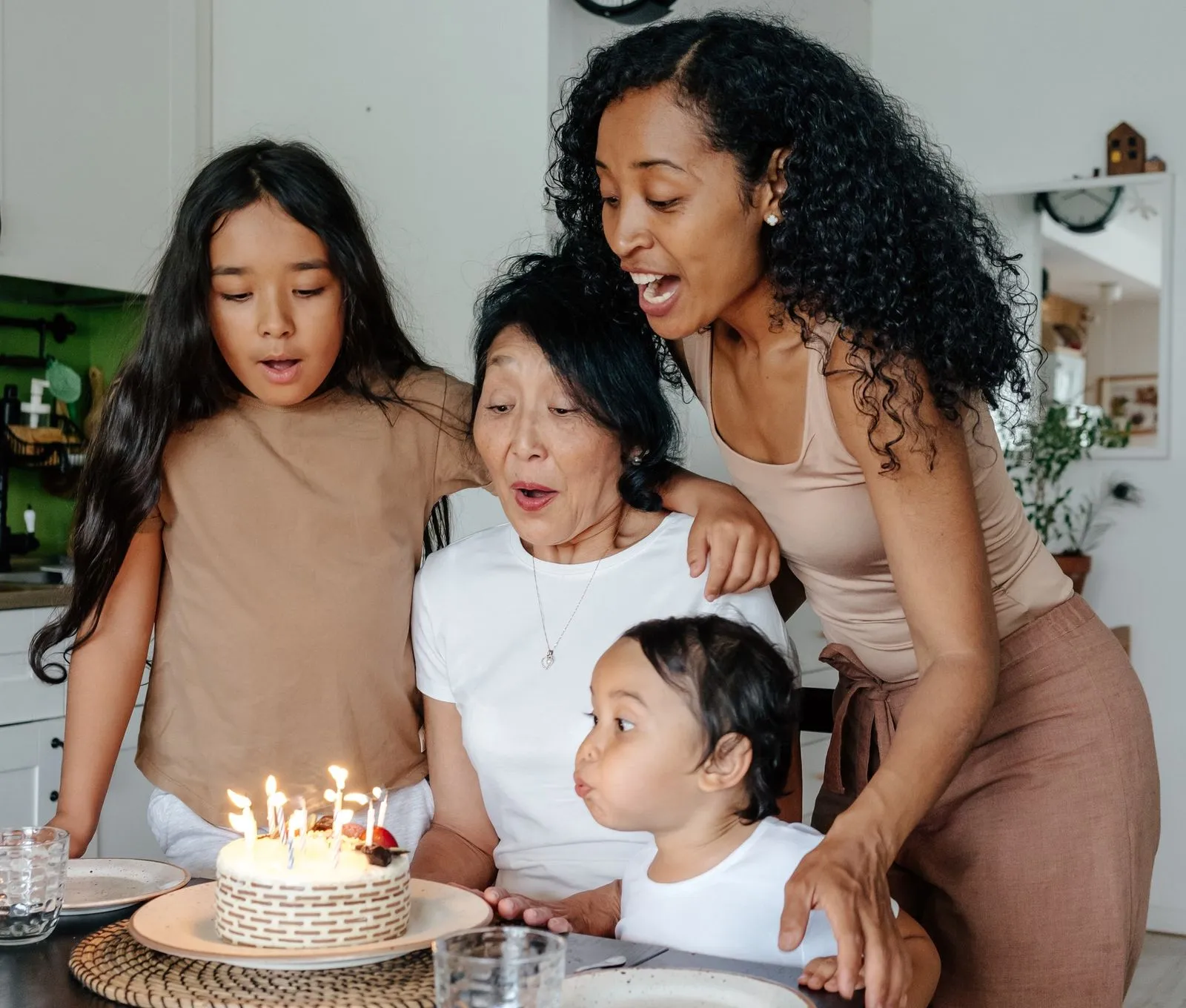 Large family celebrates a child's birthday in the kitchen, he blows out his candles